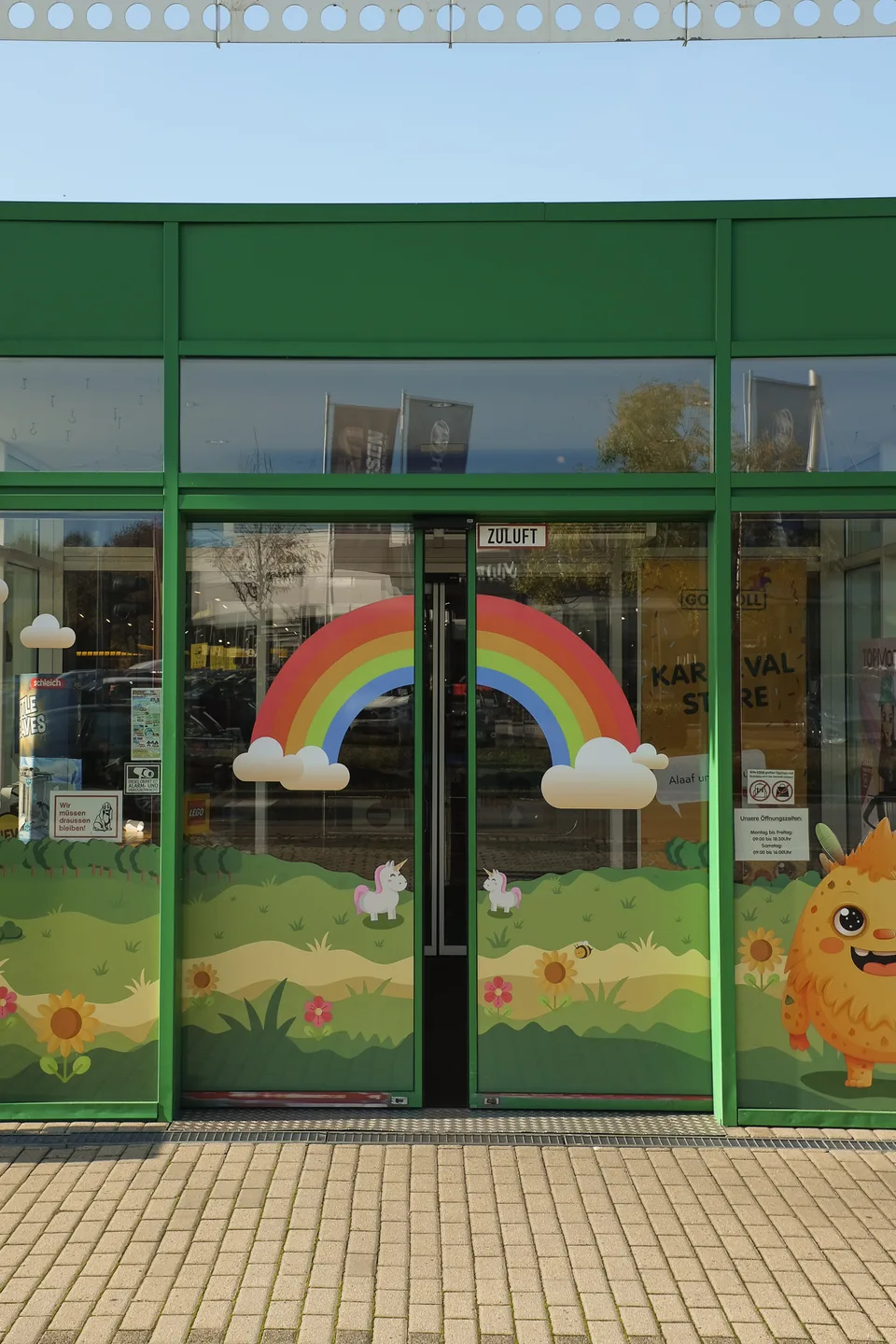 Gongoll Freizeitmarkt, Markenraum: Eingang des Marktes mit grünem Rahmen und bunter Regenbogen-Folierung