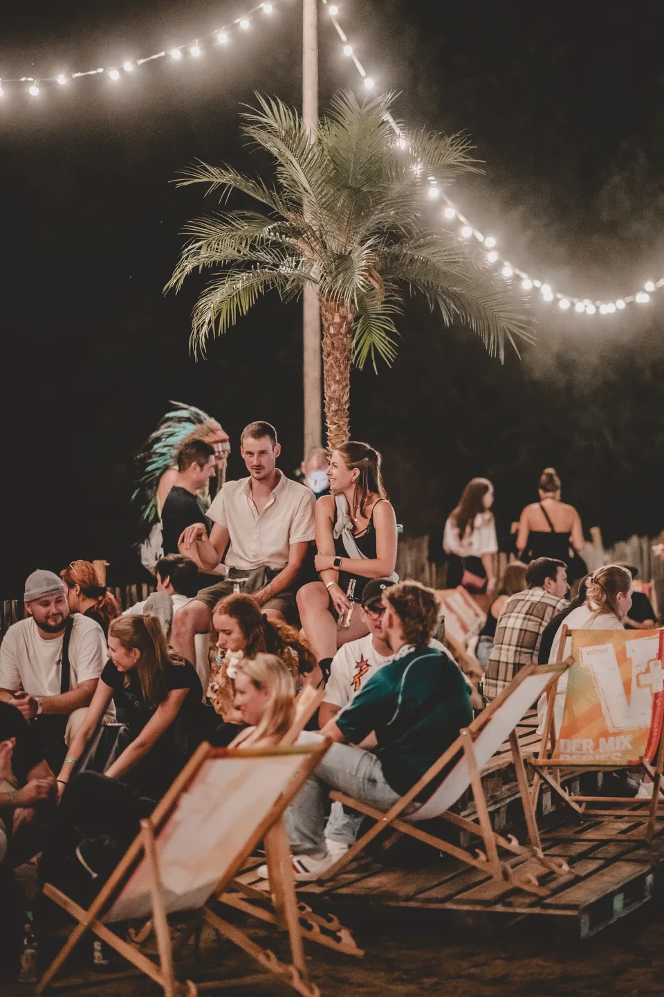 Strabi Open Air, Markenidentität: Gäste in Liegestühlen in der Lounge-Area unter Lichterketten und Palme