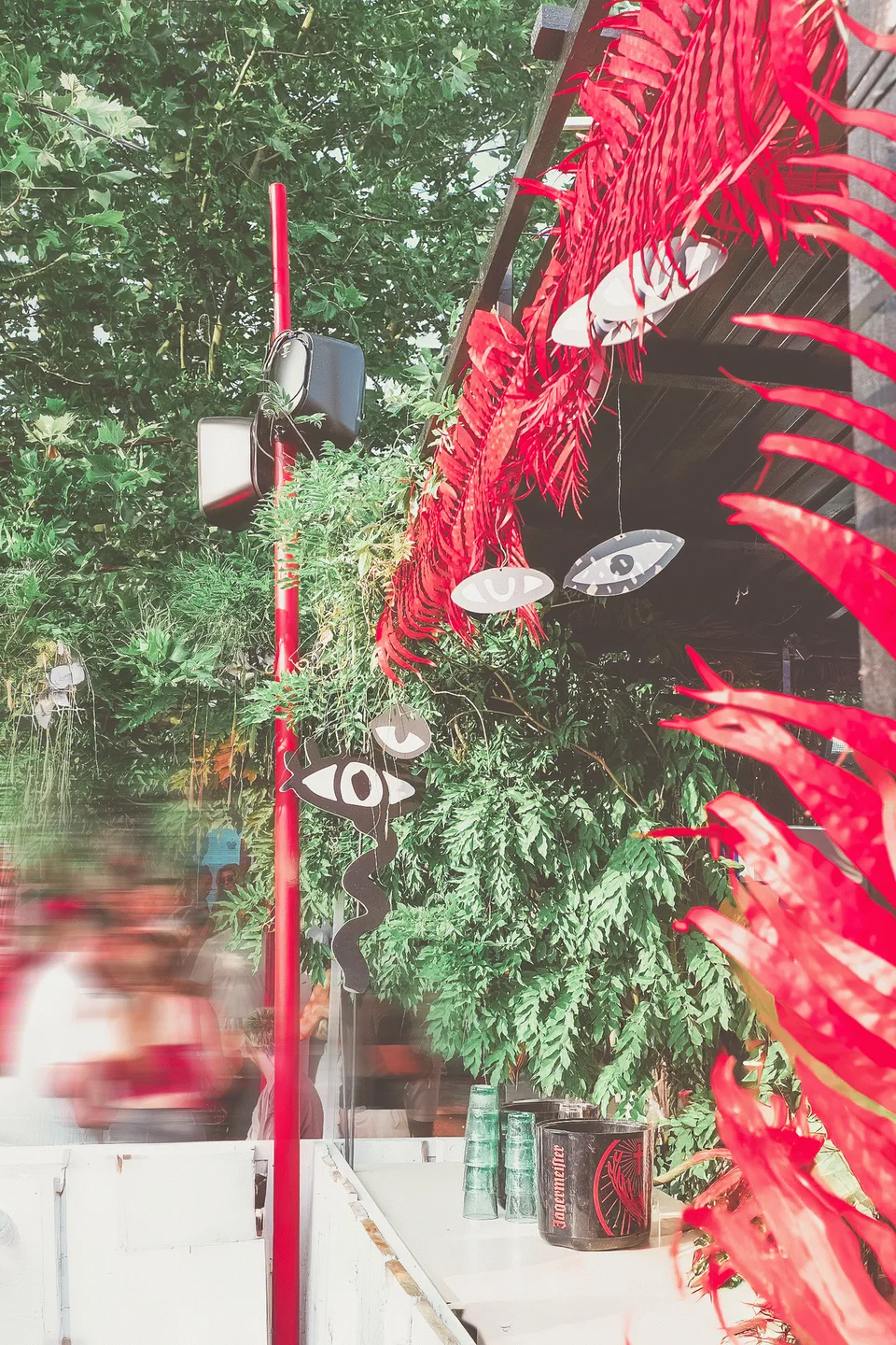 Kiesgrube Open Air, Event und Struktur: rote Palmenblätter und Lautsprecher an einem Mast zwischen grünen Bäumen