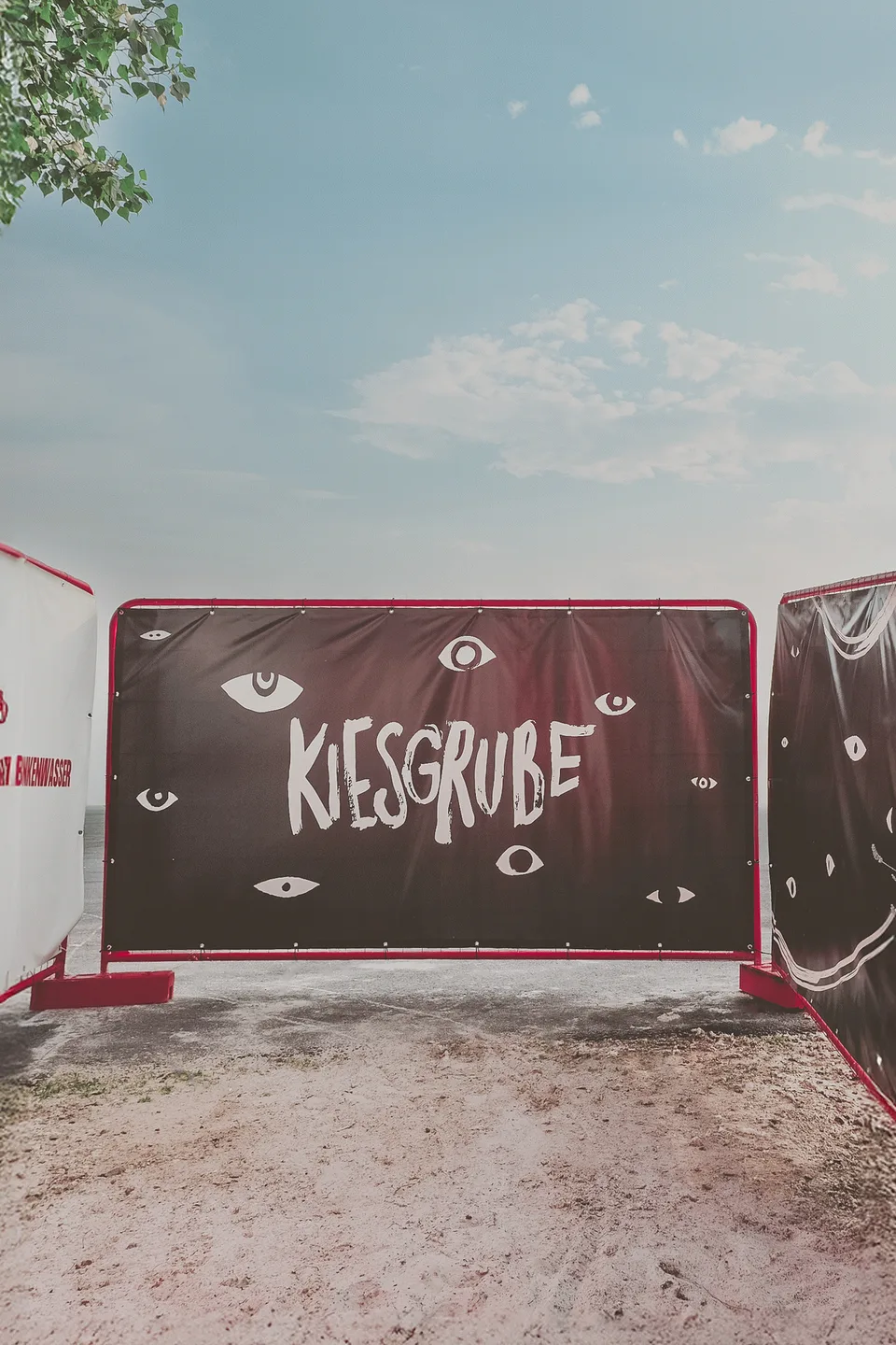 Kiesgrube Open Air, Event und Struktur: Banner mit Augen und der Schrift „Kiesgrube“ am Zaun