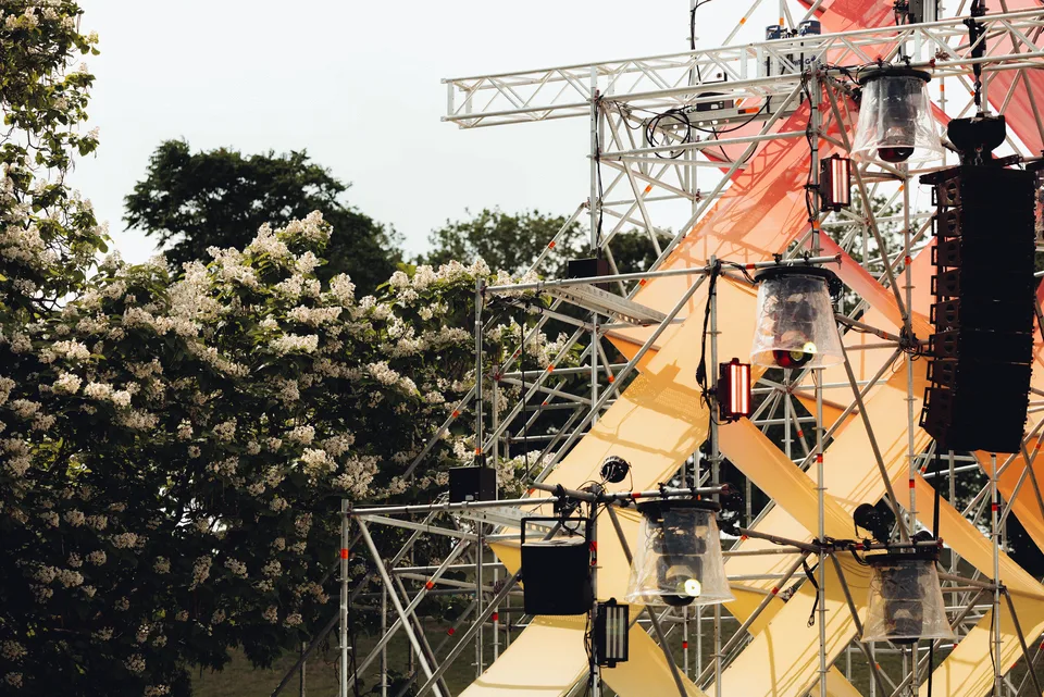Panama Open Air, Event und Struktur: Bühnengerüst mit Scheinwerfern und Lautsprechern zwischen blühenden Bäumen