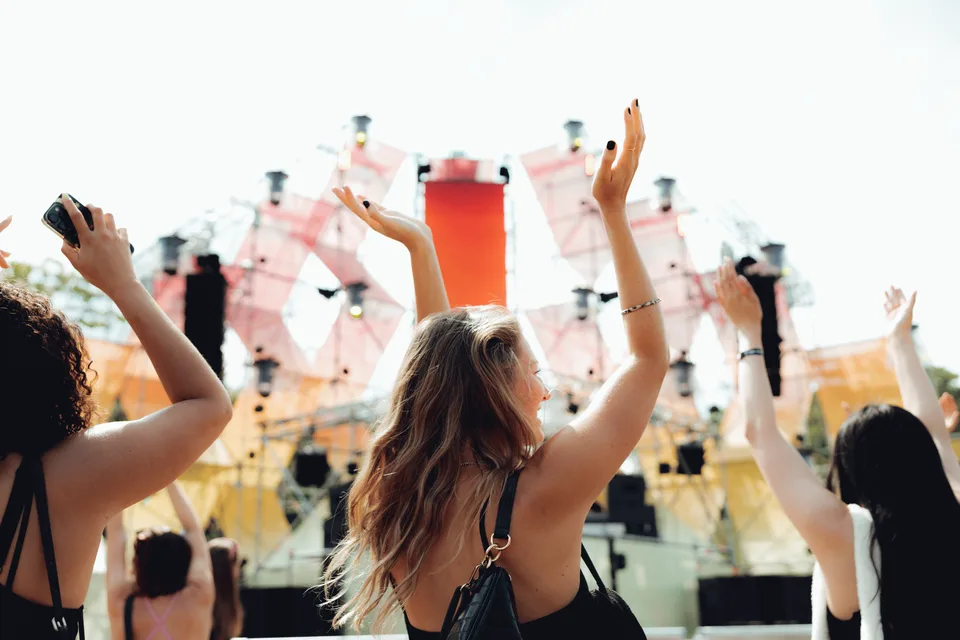 Panama Open Air, Event und Struktur: Festivalbesucher:innen mit erhobenen Armen vor der Bühne in Rosa und Gelb