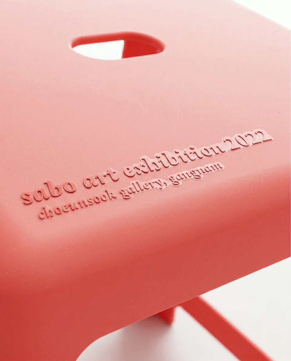 Sabo In Plastic, Markenraum: Prägung „sabo art exhibition 2022“ auf einem roten Hocker