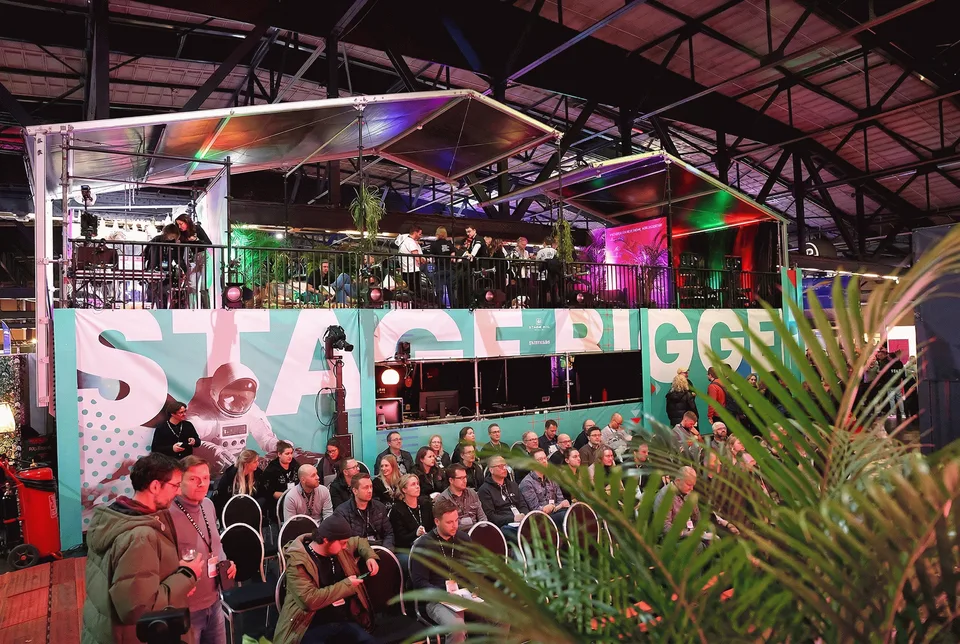 Stageventure & Friends, Event und Struktur: Gemeinschaftsstand in einer Halle mit Publikum und Schriftzug „Stage Bigger“